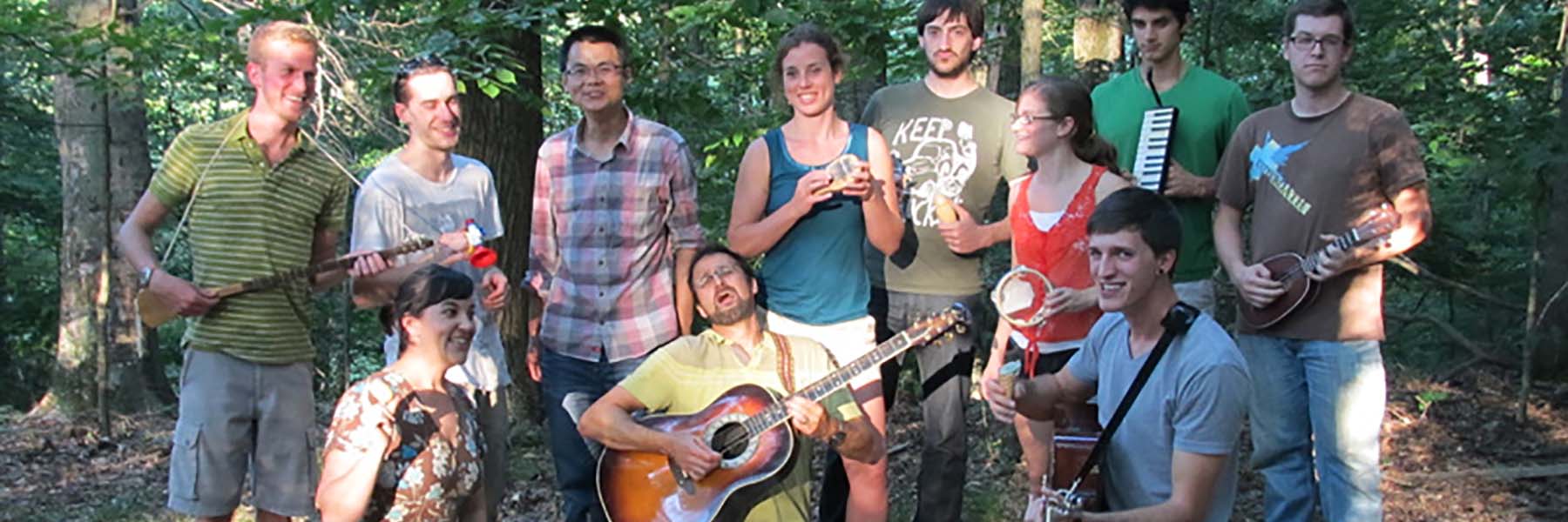 Lab members gather for a group photo in the woods with guitars and other musical instruments.