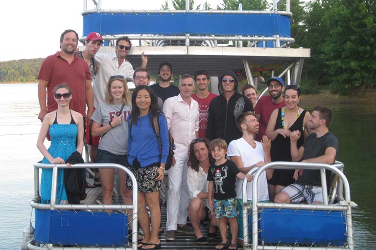Lab members and their families pose for a photo on a pontoon boat while cruising the lake during a lab boat party.